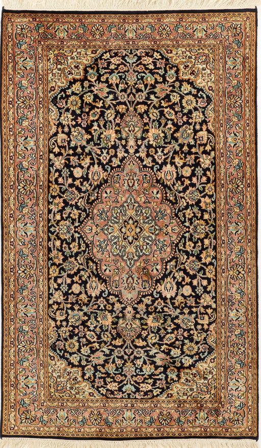 An ornate rectangular Persian-style rug with a dark navy and black field, cream floral motifs, and a detailed border in beige, gold, and muted green, finished with white fringe on the top and bottom.